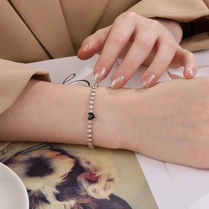 Détail d'un bracelet en or avec des zircons blancs et une pierre en forme de cœur noir