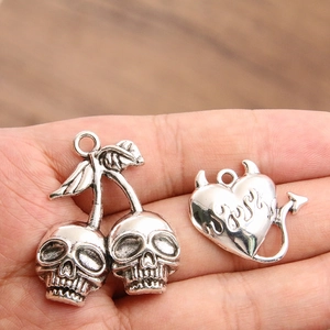 Silver skull cherry and flaming demon heart charms held in hand for DIY jewelry making
