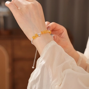 Detail view of silver bracelet with yellow citrine beads and heart-shaped pendant
