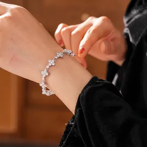 Luxurious silver clover bracelet with sparkling zircon stones worn on a woman's wrist