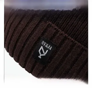 Detailed close-up of brown chunky ribbed knit hat featuring a black woven brand label