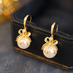 Macro shot of gold bow knot pearl earrings with zircon inlay on a luxury jewelry box