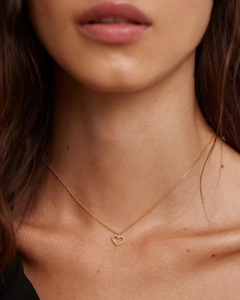 Detail of a gold heart pendant necklace with shimmering crystals on a female model neck