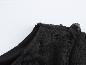 Détail de la robe en maille noire avec découpes ajourées et patchwork de dentelle fine