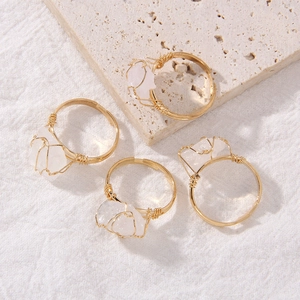 Macro shot of four handmade gold wire-wrapped rings with irregular natural raw gemstones