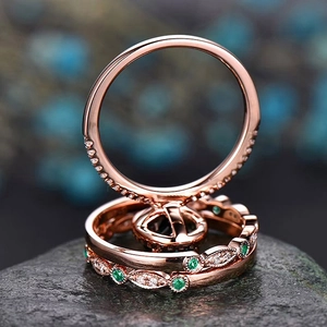 Detail of rose gold stacking rings with emerald stones and white diamonds on stone