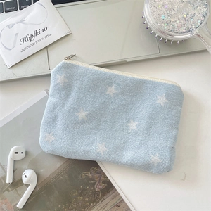 Detail of star print denim pouch with zipper on a desk with accessories