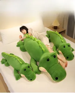 Détail de trois tailles d'oreillers en peluche crocodile vert doux sur un lit de chambre