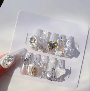 3D embossed press-on nail set with white pearl finish, ribbons, and Saturn charms