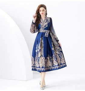 Detailed view of luxury silk texture and golden paisley print on navy V-neck wrap dress