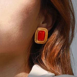 Detail of vintage gold-tone earrings with rectangular red stone on model ear