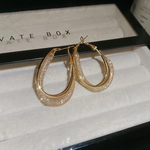 Close-up of gold U-shaped earrings with micro-pave zircons in a velvet jewelry box