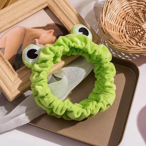 Cute green plush frog headband with cartoon eyes on a tray for face washing