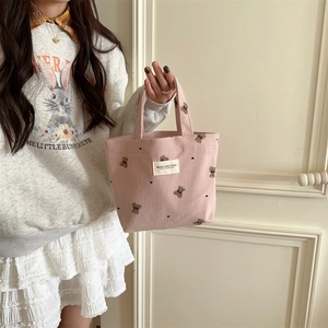 Pink corduroy tote bag with bear embroidery held by a model for size perspective