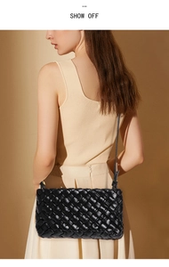 Detail of black woven pattern texture and slim shoulder strap on a chic crossbody bag