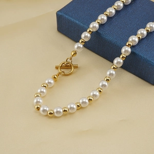 Détail d'un collier de perles avec perles dorées et fermoir à bascule OT élégant en or