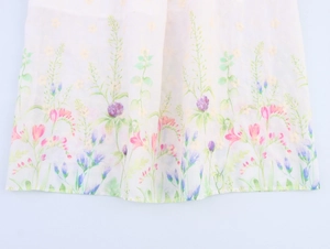 Close-up of intricate colorful floral embroidery on white french style dress fabric