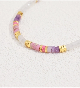 Macro shot of colorful beaded necklace with pink purple stones and 18K gold plated spacers