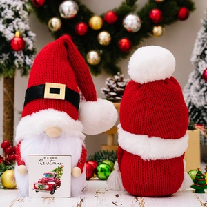 Red and white knitted Christmas gnome plush holding a Merry Christmas wooden sign