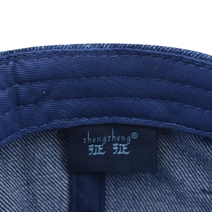 Macro detail of inner seams and brand label on a washed blue denim baseball cap