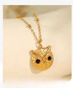 Macro detail of golden owl pendant featuring hammered texture and black stone eyes
