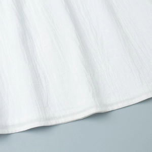 Detailed close-up of white pleated fabric texture with neat hemline stitching detail