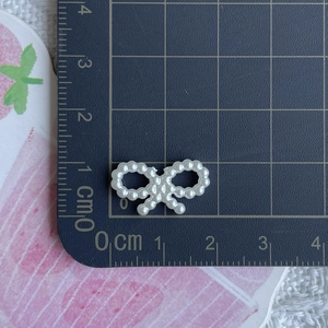 Close-up of white ABS pearl bow charm on a measuring mat showing 1.8cm width size