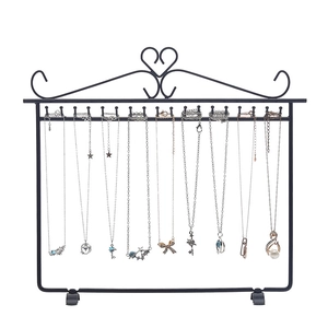 Black iron necklace display rack with heart top and multiple hooks on white background