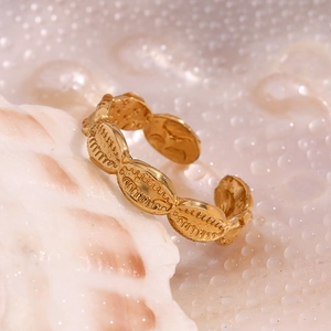 Detail of gold-plated tooth-shaped adjustable ring on a shell with water droplets
