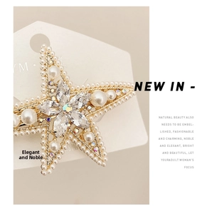 Macro shot of gold star hair clip with pearls and marquise crystals on card