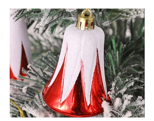 Close-up of a red festive Christmas bell ornament with snow effect on pine branches