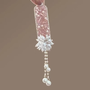 Detail of pink crystal beads and long pearl tassel on a handmade luxury metal hair clip