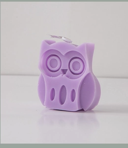 Detailed view of a purple owl-shaped decorative candle featuring clean carved lines