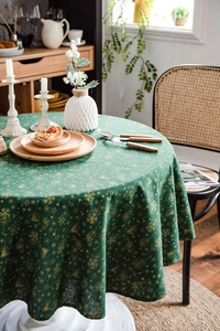 Close-up of dark green Christmas tablecloth with gold foil snowflakes on a round table