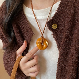 Close-up of bagel-shaped pendant necklace with brown suede cord on a winter sweater