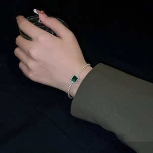 Detailed close-up of emerald green geometric bracelet with sparkling zircon stones