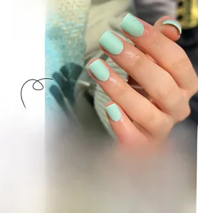 Macro shot of mint green matte press-on nails in square shape showing application detail