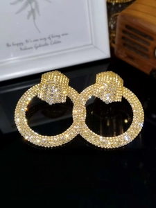 Macro shot of large golden hoop earrings with sparkling white crystals inlay