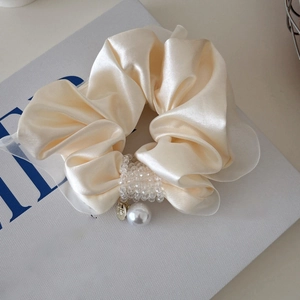 Detailed macro view of cream satin scrunchie with crystal beads and white pearl charm