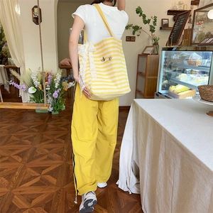 Detailed close-up of yellow and white striped canvas tote with lace bow and butterfly embroidery
