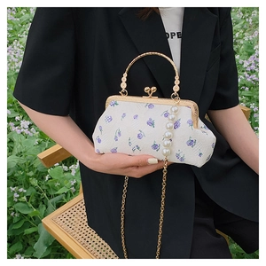 Detail of vintage shell bag with purple floral embroidery and pearl chain strap