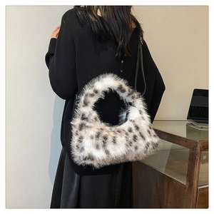 Plush leopard print crescent bag shown on shoulder to display size and style