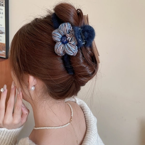 Vue détaillée d'une pince à cheveux fleur tricotée bleu marine sur cheveux bruns