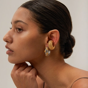 Close-up of model wearing textured gold hoops and silver floral earrings in stainless steel