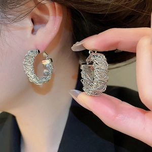 Detail view of silver round hoop earrings featuring an intricate woven metal texture for women