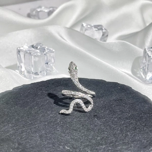 Detail of silver snake ring with pavé diamonds and green gemstone eyes on stone