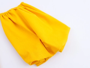 Detailed close-up of the elastic waistband and pleated fabric on the yellow off-shoulder dress
