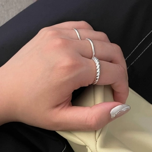 Detailed view of silver twisted knot ring and minimalist band on model's hand