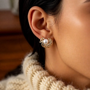 Macro shot of 18k gold feather earring with white pearl and sparkling crystals