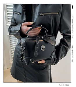 Detail of black PU leather box bag featuring metal skull ornament and rivet corners